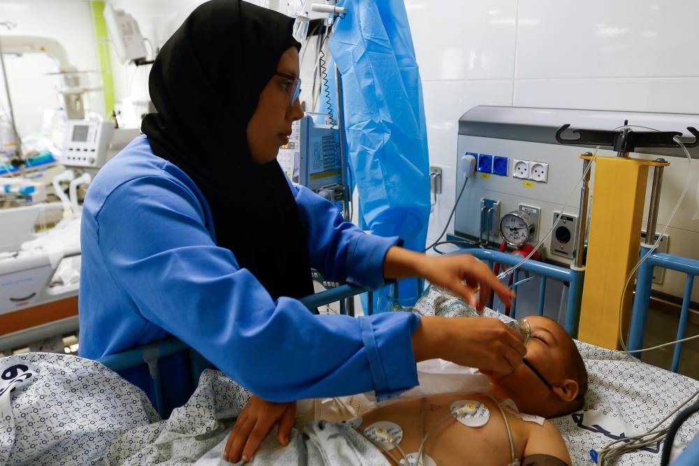 A medical worker assists a Palestinian boy, who was wounded in Israeli strikes, at the Intensive Care Unit (ICU) of Nasser hospital, as doctors say they are only able to accept critical cases that are in need of surgery, while the unit is filled up with victims of the ongoing conflict with Israel, in Khan Younis, in the southern Gaza Strip, Thursday. REUTERS