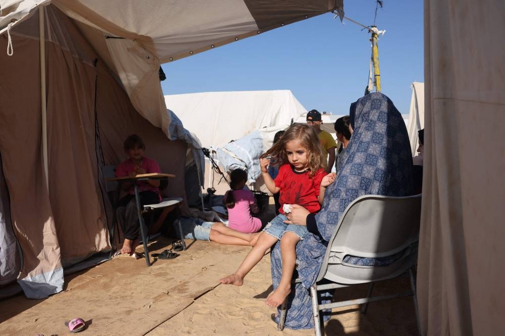 Displaced Palestinians, who fled their houses amid Israeli strikes, shelter in tents set up in a United Nations-run center, in Khan Yunis, in the southern Gaza Strip on October 26. AFP
