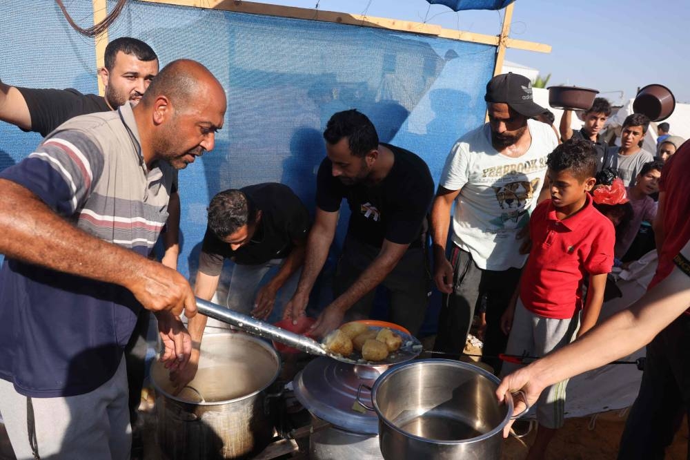 Displaced Palestinians, who fled their houses amid Israeli strikes, shelter in tents set up in a United Nations-run center, in Khan Yunis, in the southern Gaza Strip on October 26. AFP