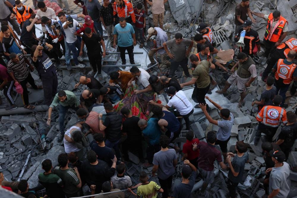 Rescuers and people remove a body from under the rubble of a collapsed building following an Israeli air strike on Rafah in southern Gaza Strip on October 26. AFP