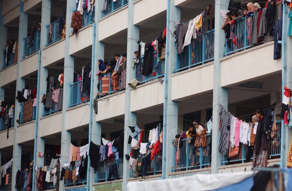 Palestinians, who have fled their homes due to Israeli strikes, watch a nearby Israeli strike as they take shelter in a UN-run school, in Khan Younis in the southern Gaza Strip, Friday.  REUTERS