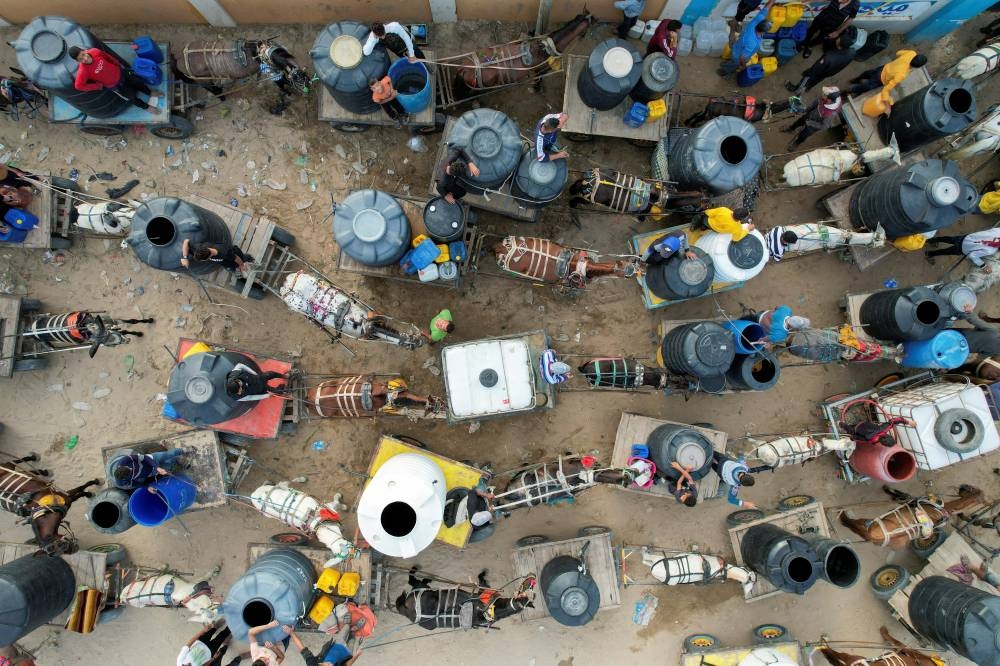 Palestinians with animal-drawn carts collect water from a water desalination plant, amid water shortages in central Gaza Strip Friday. REUTERS