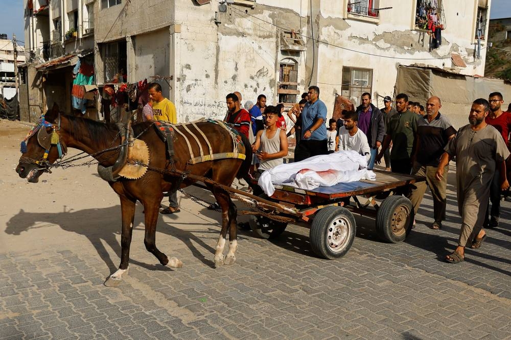 People transport on a horse-drawn cart the bodies of Palestinians killed in Israeli strikes, amid shortages of fuel, during their funeral in Khan Younis, in the southern Gaza Strip Friday. REUTERS
