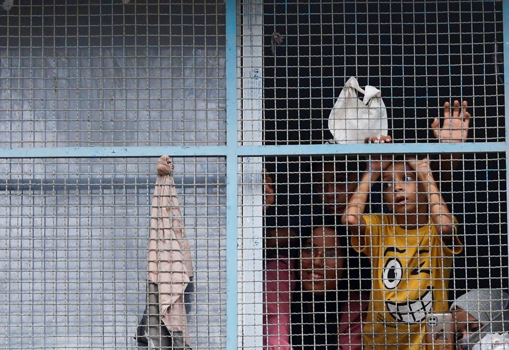 Palestinian children, who have fled their homes due to Israeli strikes, watch a nearby Israeli strike as they take shelter in a UN-run school, in Khan Younis in the southern Gaza Strip, Friday.  REUTERS