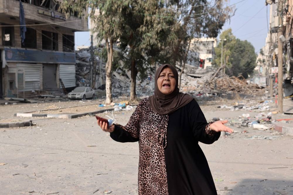 A woman reacts as she stands in front of buildings damaged in Israeli strikes in Gaza City on Saturday. AFP