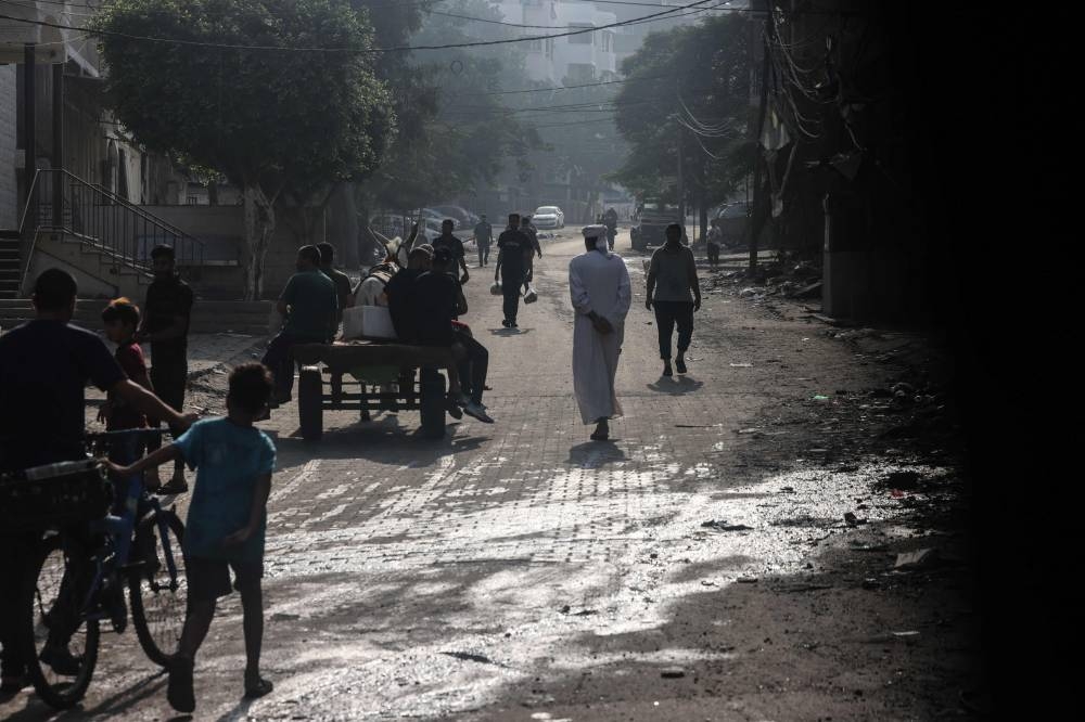 People walk along a street in the aftermath of Israeli strikes in Gaza City on Saturday. AFP