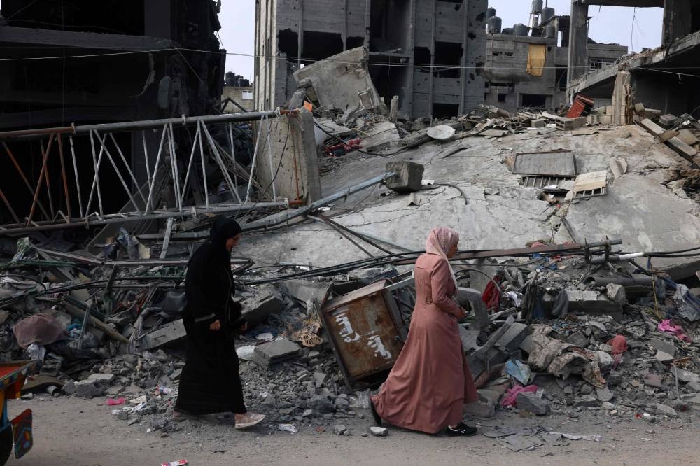 Women walk past a destroyed building in the aftermath of Israeli bombing in Rafah in the southern Gaza Strip on Saturday. AFP