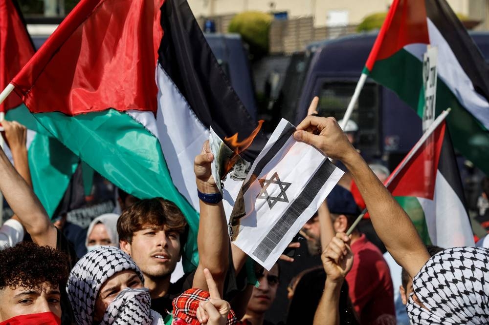 Palestinian youth burn Israeli symbols outside the Israeli embassy, during a pro-Palestinian protest in Athens, Greece, Sunday. REUTERS