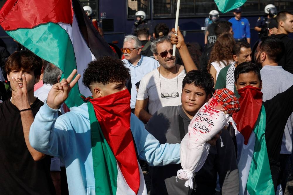 A Palestinian protester holds a doll with red paint stains outside the Israeli embassy during a pro-Palestinian protest in Athens, Greece, Sunday. REUTERS