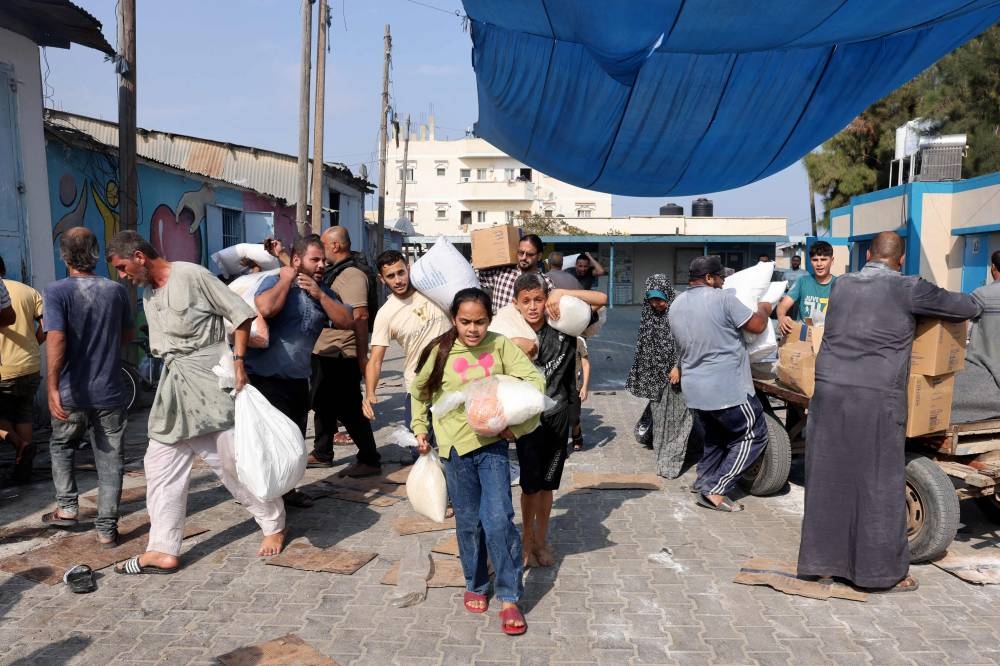 Palestinians storm a UN-run aid supply center, that distributes food to displaced families in Deir al-Balah on Saturday. AFP