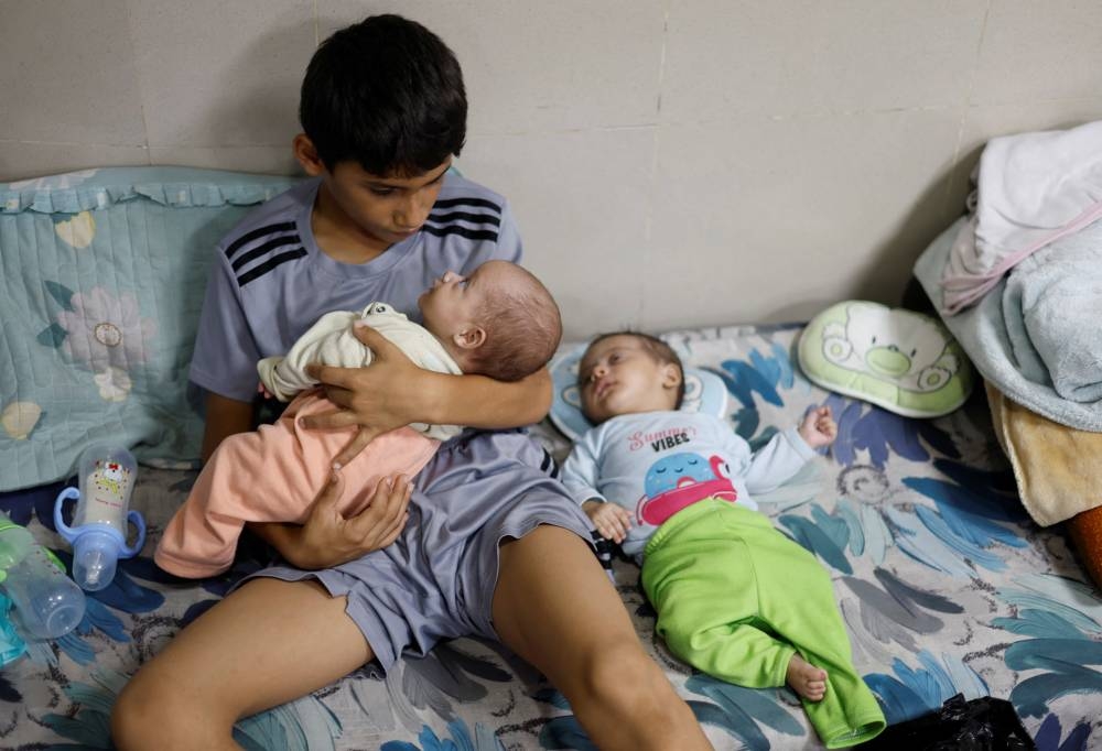 A displaced Palestinian boy, who fled with his family from their house amid Israeli strikes, looks after his twin siblings as they take shelter at Nasser hospital in Khan Younis in the southern Gaza Strip, Sunday. REUTERS