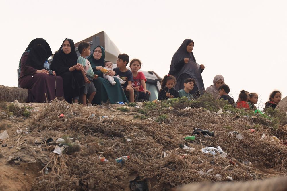 Palestinian women and children sit along the sea front in Deir el-Balah in the southern Gaza Strip, on Sunday. AFP