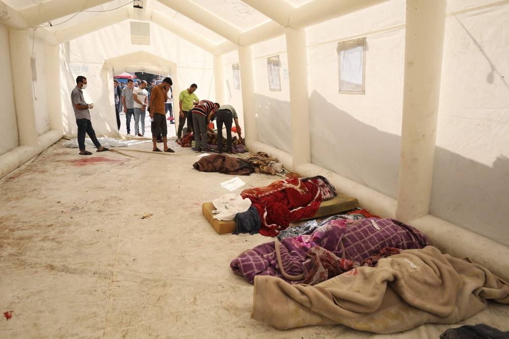 Palestinians identify relatives as bodies are lined up on the ground inside a tent at Al-Shifa hopsital in Gaza City, Sunday. REUTERS