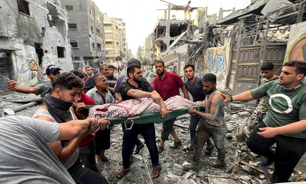 Palestinians carry a casualty at the site of Israeli strikes on houses, in Gaza City Saturday. REUTERS