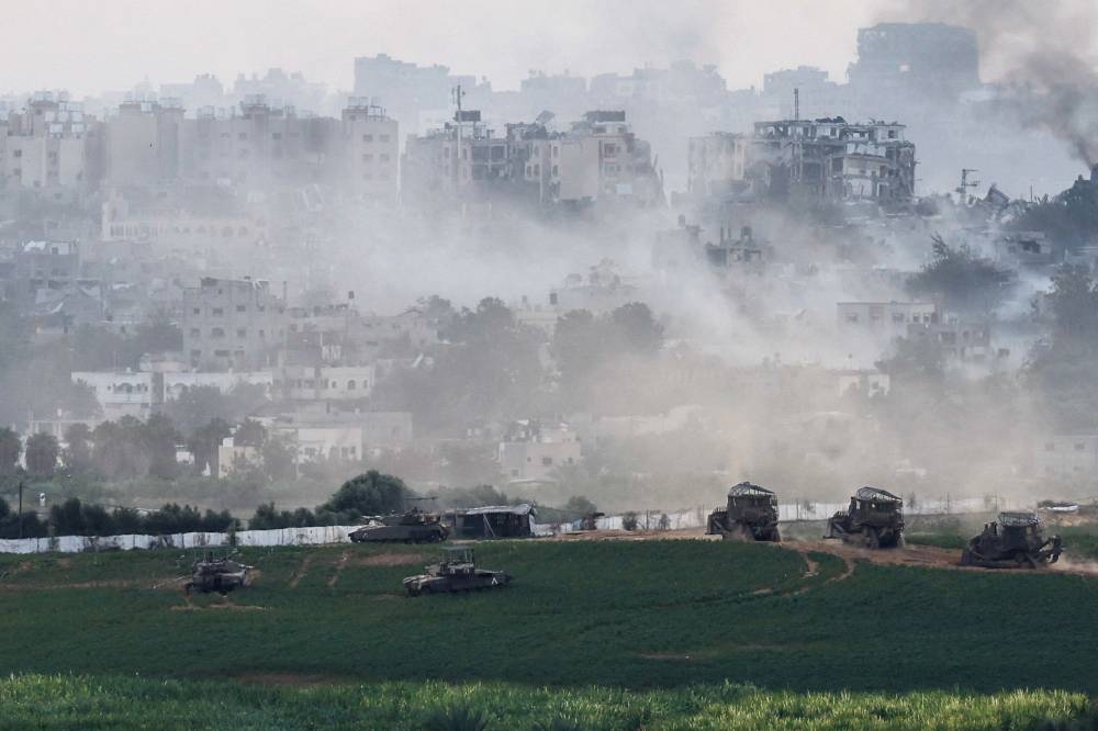 Israeli tanks and  other military vehicles manoeuvre inside the Gaza Strip, as seen from Israel, Sunday. REUTERS