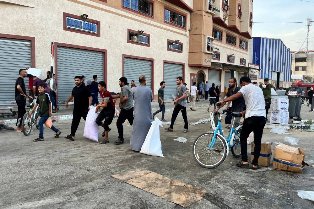 Palestinians carry food supplies near a United Nations Palestinian refugee agency (UNRWA) run warehouse in Khan Younis in the southern Gaza Strip on Saturday. REUTERS