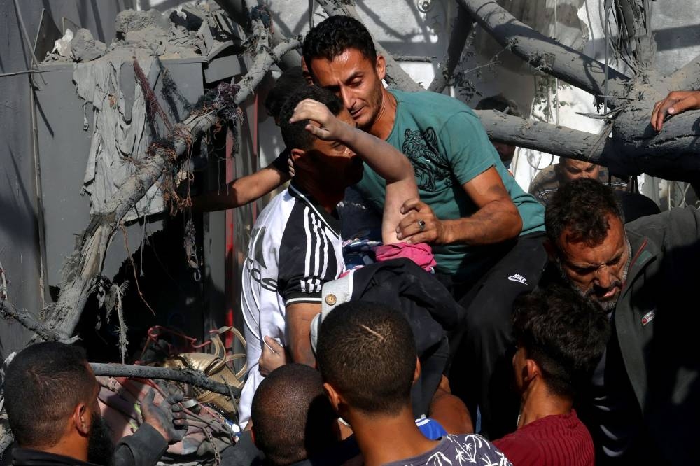 A Palestinian woman is rescued from a collapsed home following an Israeli air strike in Rafah, in the southern Gaza Strip on Monday. AFP
