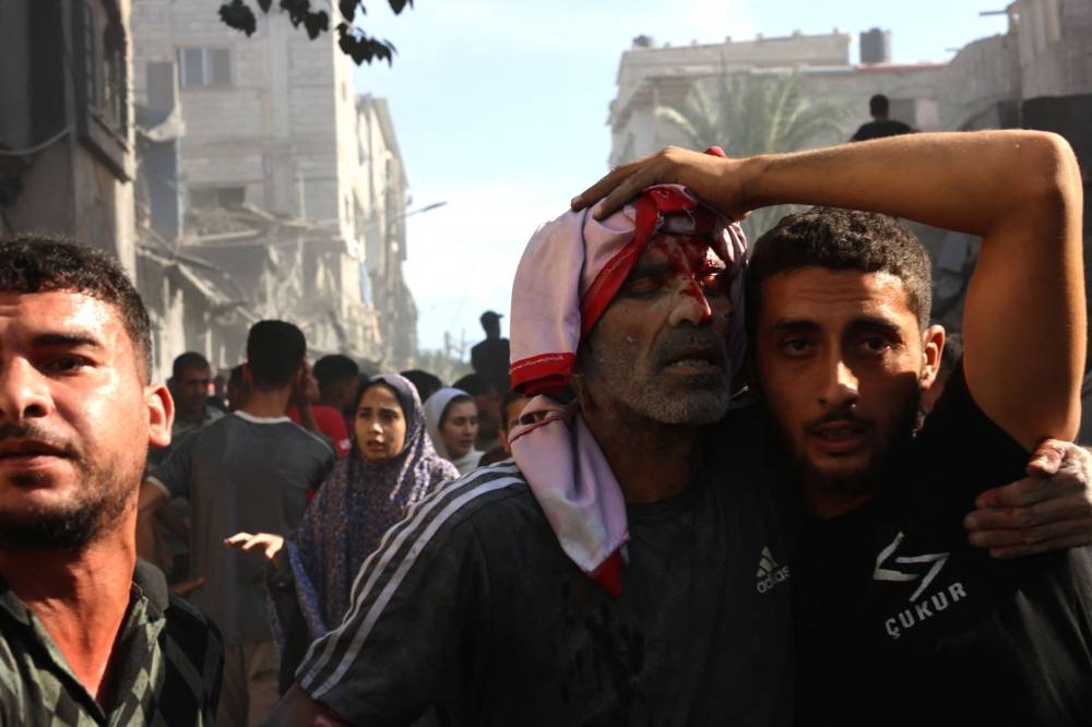 A Palestinian man is helped following an Israeli air strike on a home in Rafah, in the southern Gaza Strip on Monday. AFP
