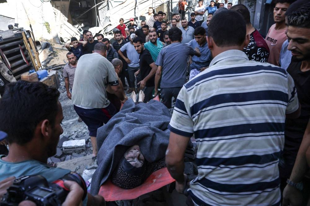 A Palestinian woman is rescued from a collapsed home following an Israeli air strike in Rafah, in the southern Gaza Strip on Monday. AFP