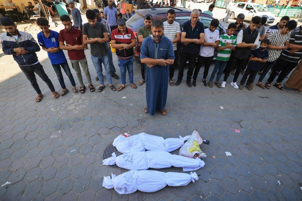  Palestinians pray by bodies of members of the al-Sarsak family killed following Israeli bombardment, before moving them for burrial in front of Al Aqsa Martyrs Hospital in Deir al-Balah in the central Gaza Strip, Monday. AFP
