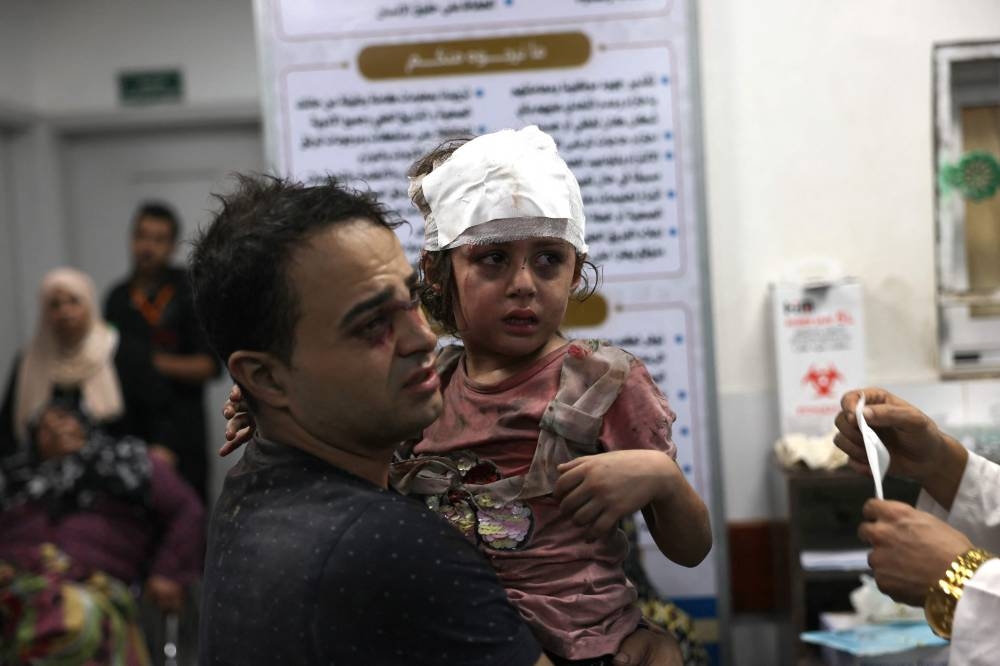 A Palestinian man carries his injured daughter at the Najjar hospital following an Israeli air strike on a home in Rafah, in the southern Gaza Strip on Monday. AFP