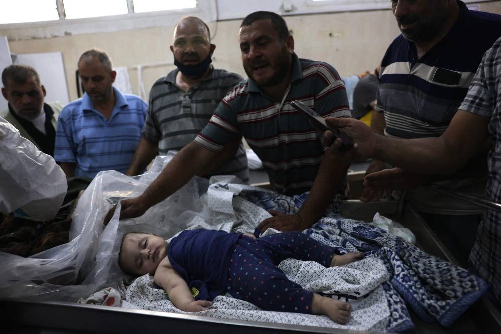 A man covers the body of a baby with a cloth as it is made ready for burial at the Najjar hospital following an Israeli air strike on a home in Rafah, in the southern Gaza Strip on  Monday. AFP
