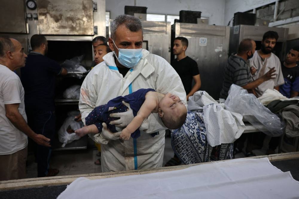 A medic places the body of a baby on a shroud as it is made ready for burial at the Najjar hospital following an Israeli air strike on a home in Rafah, in the southern Gaza Strip on  Monday. AFP
