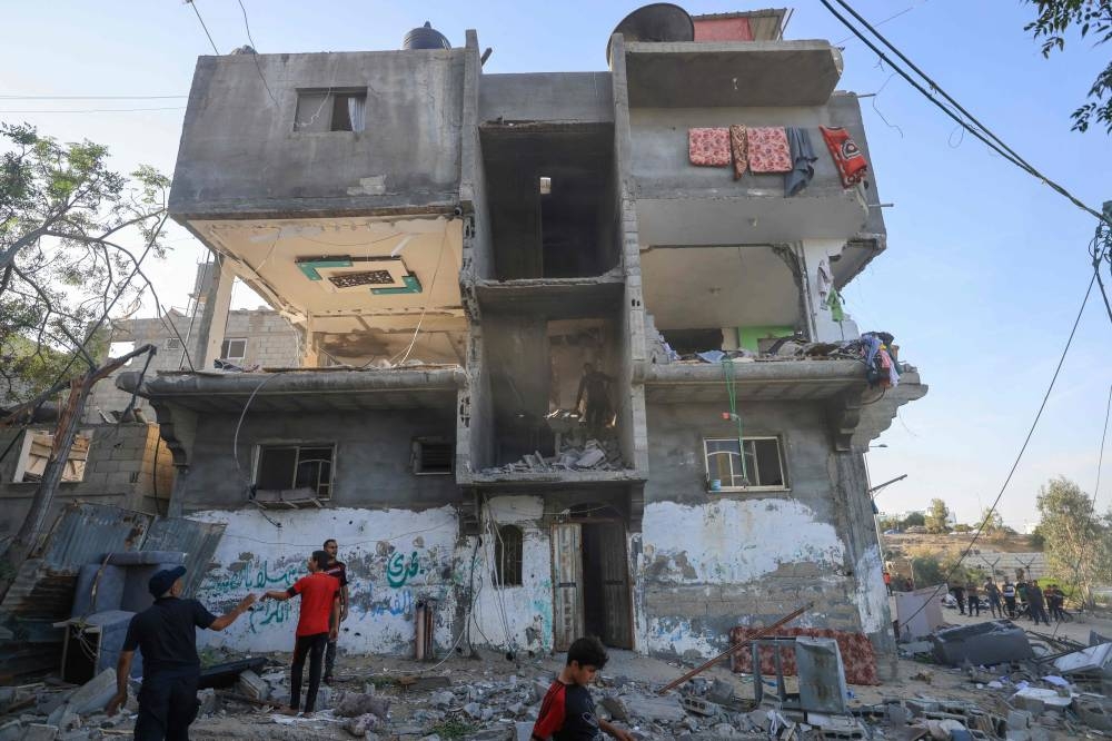 Palestinians search a damaged building following Israeli strikes in Khan Yunis in the southern Gaza Strip on Monday. AFP