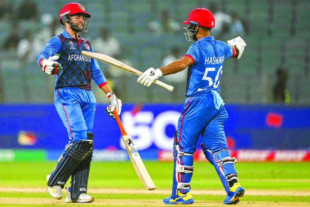 Afghanistan’s Azmatullah Omarzai (left) celebrates with his captain Hashmatullah Shahidi after scoring a half-century during the 2023 ICC Men’s Cricket World Cup match against Sri Lanka in Pune on Monday. (AFP)