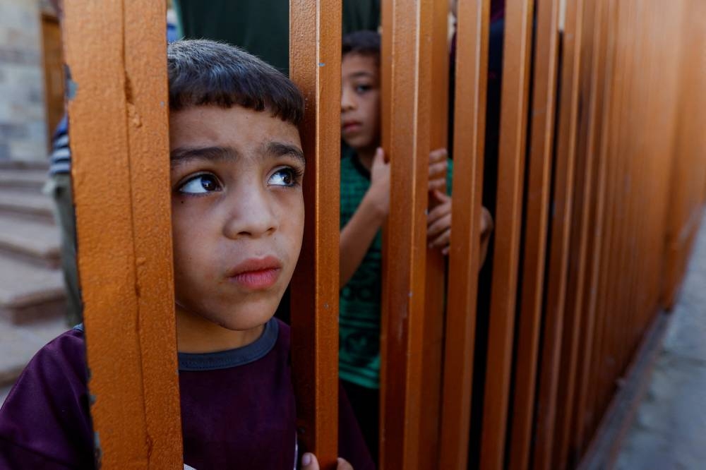 A child looks on from behind a gate as mourners react near the bodies of Palestinians killed in Israeli strikes during their funeral, in Khan Younis in the southern Gaza Strip Tuesday. REUTERS