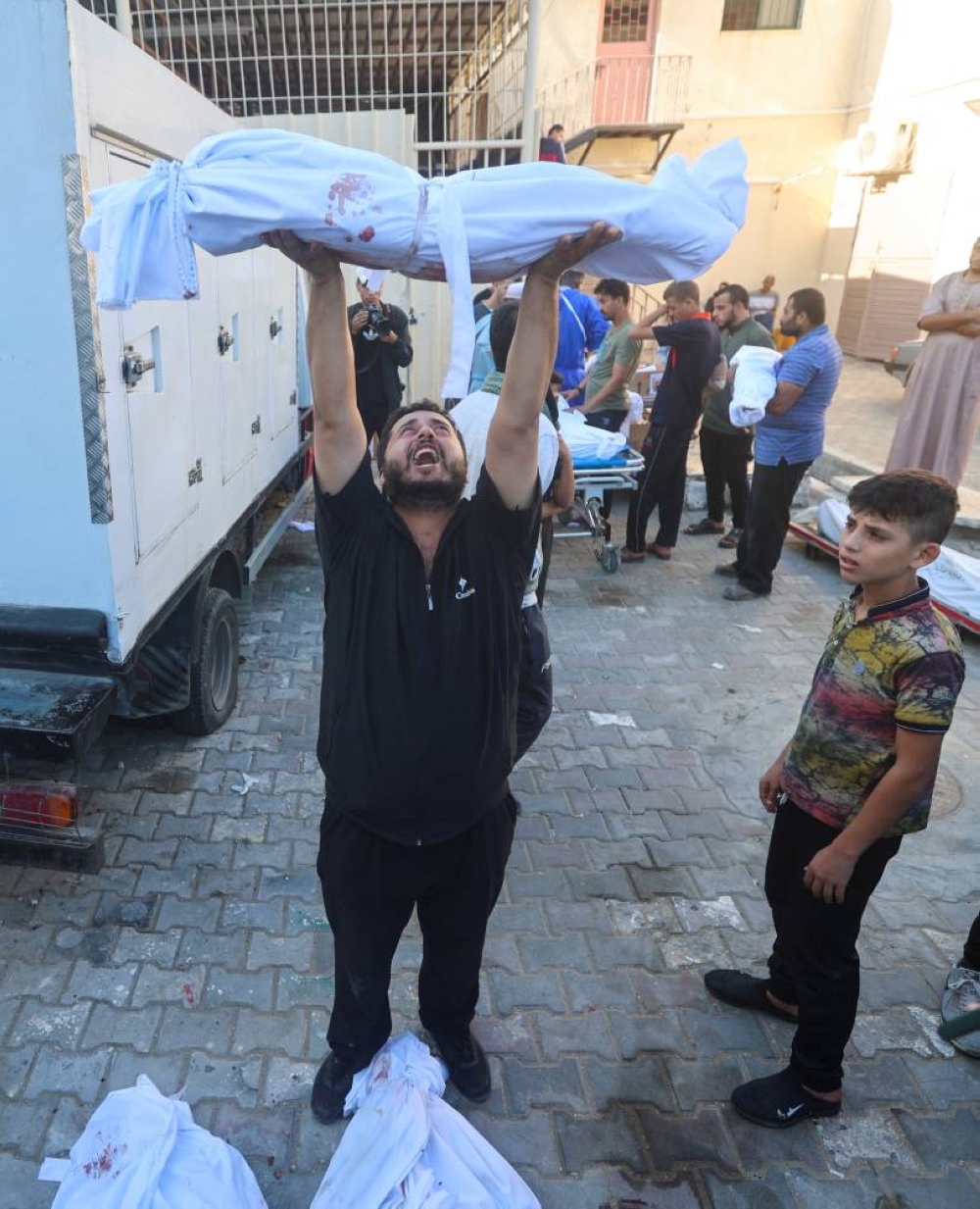 A Palestinian man from al-Badrasawi family carries the body of his child who was killed in Israeli strikes, at Shuhada Al-Aqsa hospital in the central Gaza Strip Tuesday. REUTERS