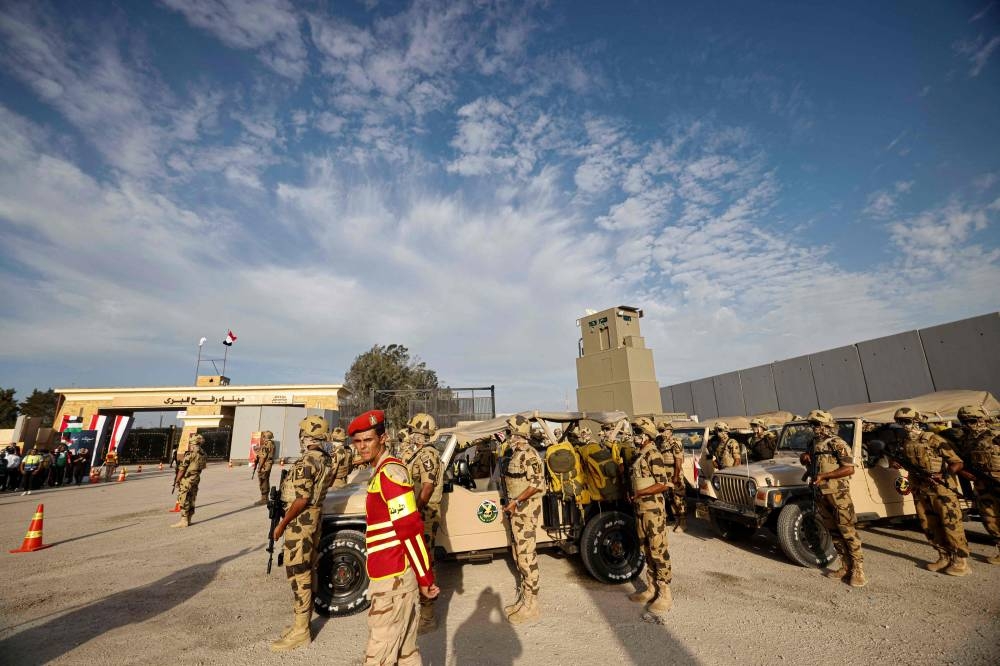 Egyptian soldiers stand guard during a visit by Prime Minister Mostafa Madbouli (unseen) to the Rafah crossing border on Tuesday. More than 30 aid trucks entered Gaza on Monday, the largest convoy to the war-ravaged Palestinian territory since deliveries began trickling in again over a week ago, the UN said. 