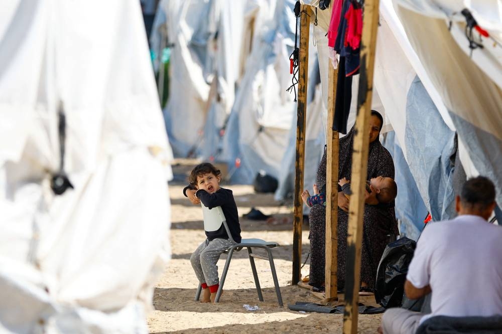 A child sits on a chair as displaced Palestinians, who fled their houses amid Israeli strikes, take shelter at a tent camp at a United Nations-run centre, in Khan Younis in the southern Gaza Strip, on Monday. REUTERS