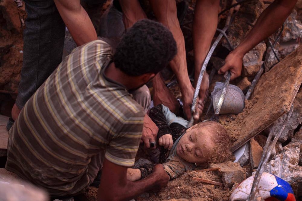 Palestinians dig out the body of a child from the rubble of a building in the Nuseirat refugee camp, in the central Gaza Strip on Tuesday. AFP