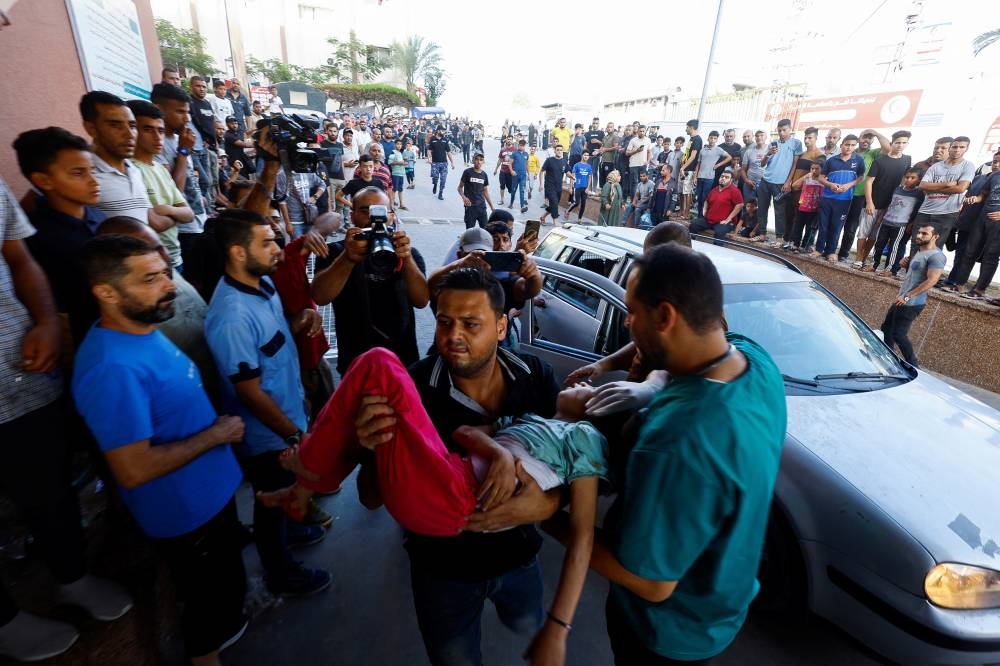 A Palestinian man carries a child casualty following Israeli strikes, at Nasser hospital in Khan Younis in the southern Gaza Strip, on Monday. REUTERS
