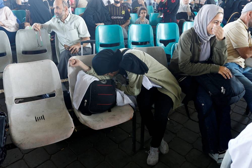 A woman rests, as Palestinians with dual citizenship wait at the Rafah border crossing with Egypt, in the hope of getting permission to leave Gaza, on Wednesday. REUTERS
