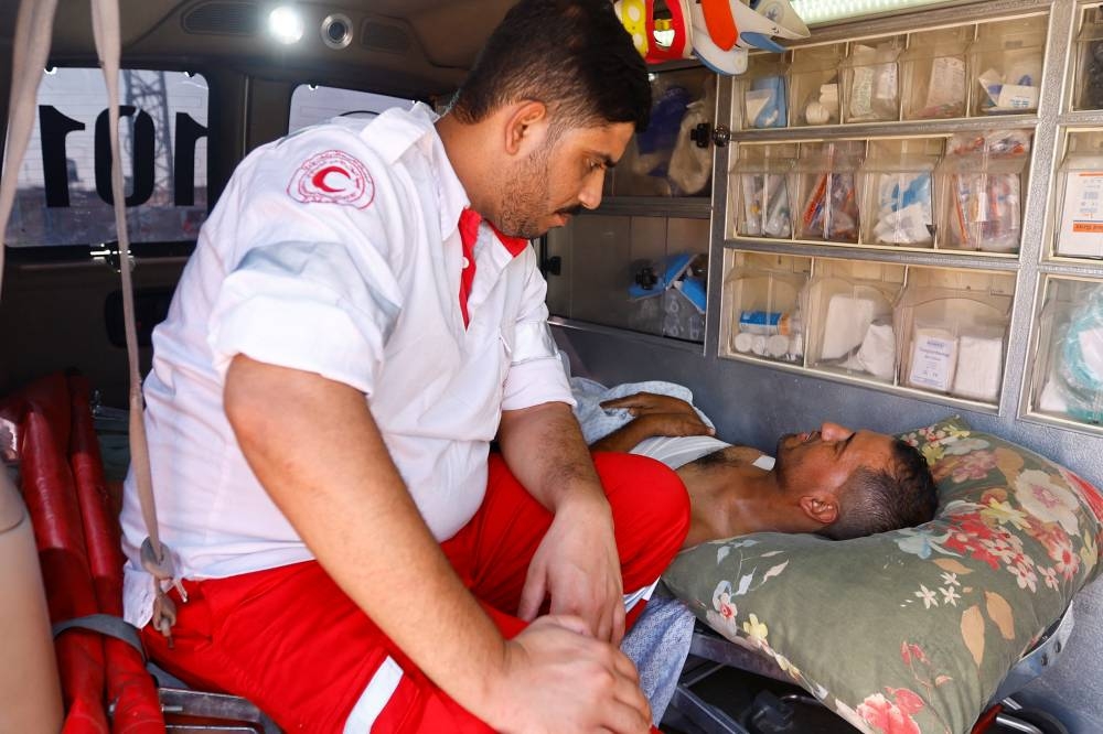 A medical worker speaks to an injured Palestinian, who will receive treatment in an Egyptian hospital, at the Rafah border crossing with Egypt, in the southern Gaza Strip, on Wednesday. REUTERS