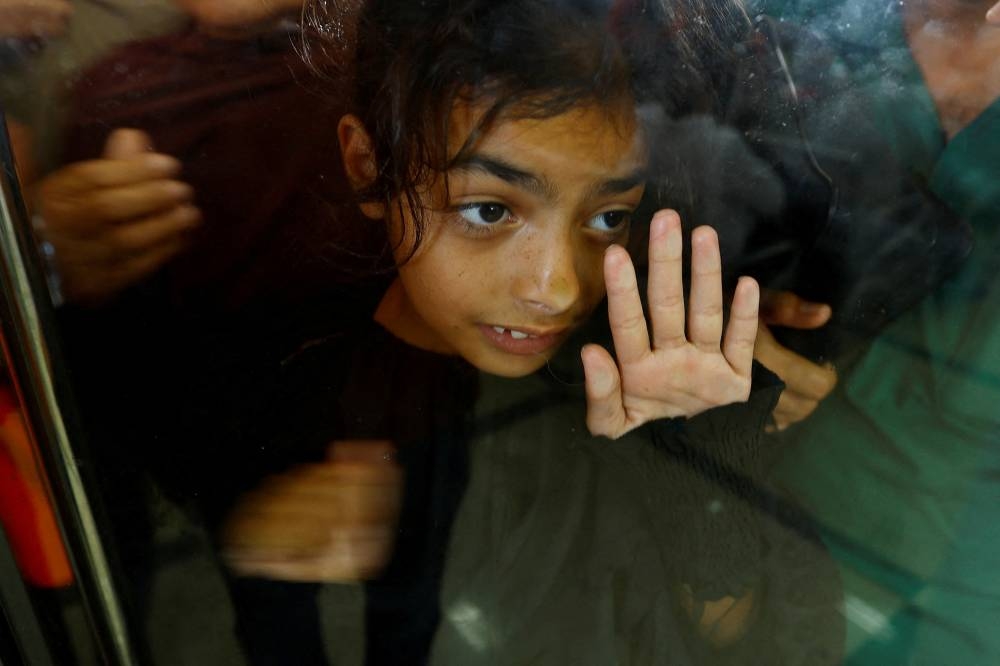 A child looks through glass, as Palestinians with dual citizenship wait at the Rafah border crossing with Egypt, in the hope of getting permission to leave Gaza, on Wednesday. REUTERS
