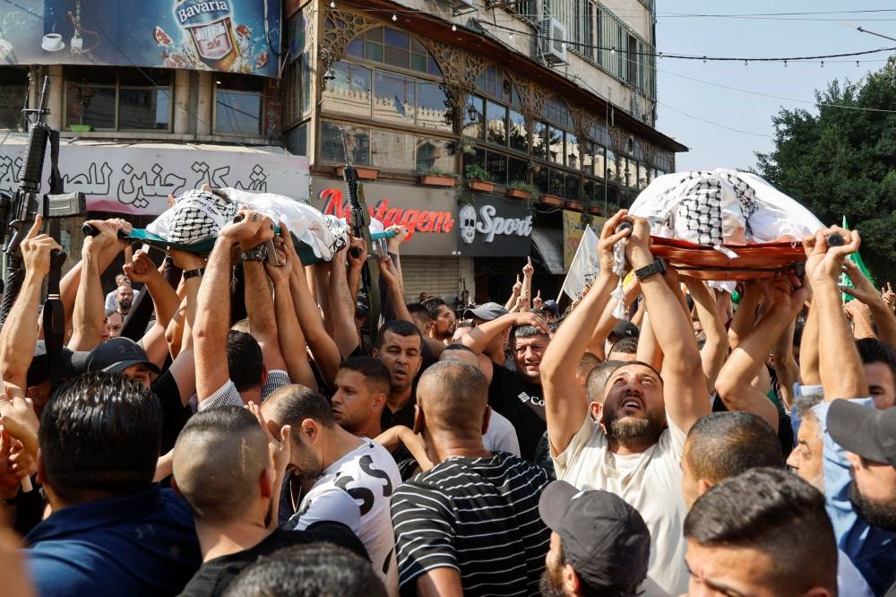 Mourners carry bodies of Palestinians who were killed in an Israeli raid, at the Jenin refugee camp, in Jenin in the Israeli-occupied West Bank, , Wednesday. REUTERS