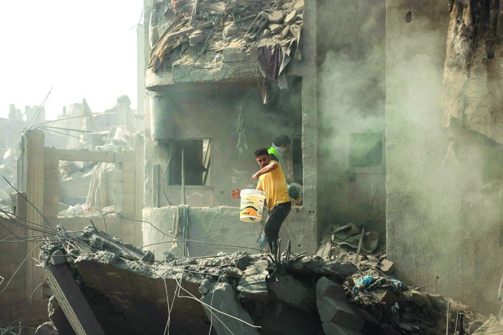 
Men pour water over the smouldering rubble of a building destroyed in an Israeli strike on the Bureij refugee camp in the central Gaza Strip. 