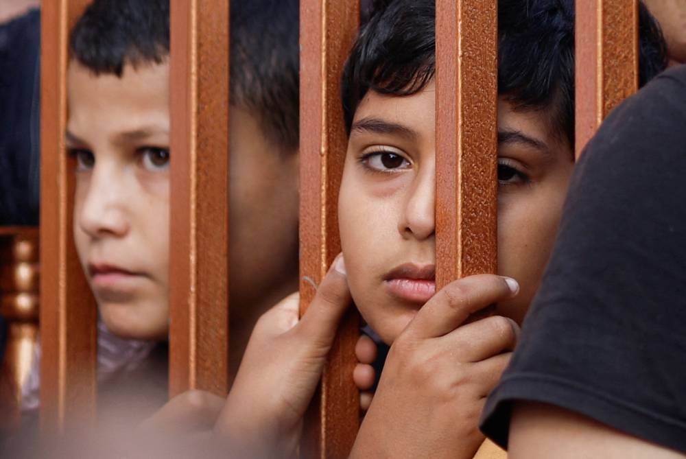 Boys react from behind a gate as the bodies of Palestinians killed during Israeli strikes are laid on the ground at a hospital in Khan Younis in the southern Gaza Strip, on Friday. REUTERS