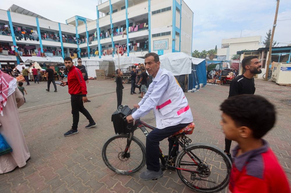 Palestinian doctor Hassan Zain al Din, who travels on his bicycle from one makeshift shelter to another to provide treatment and medication to displaced patients, arrives at a school turned into a shelter, amid fuel shortages, in Deir al-Balah, in the central Gaza Strip. REUTERS