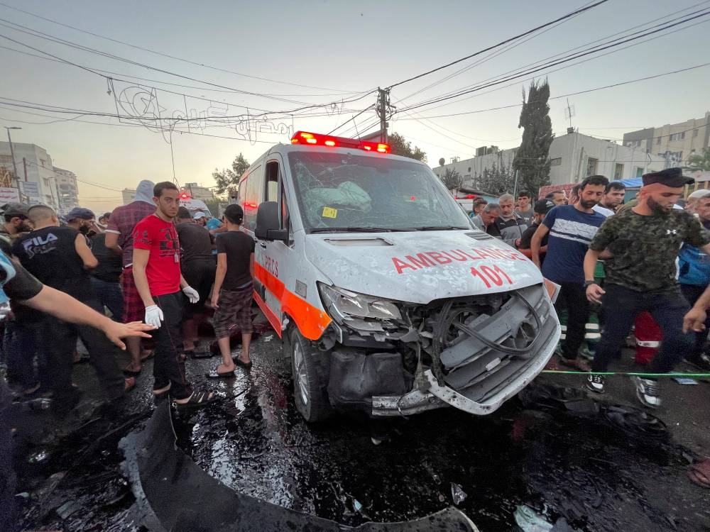 Palestinians check the damages after a convoy of ambulances was hit, at the entrance of Shifa hospital in Gaza City, Friday. REUTERS