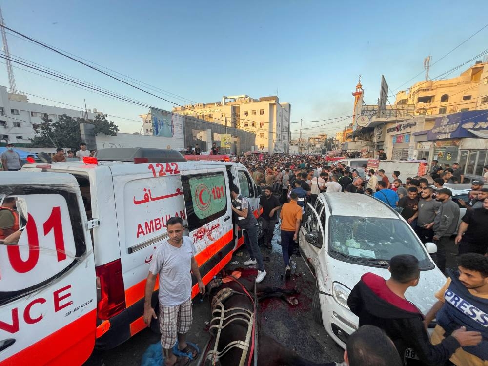 Palestinians check the damages after a convoy of ambulances was hit, at the entrance of Shifa hospital in Gaza City, Friday. REUTERS
