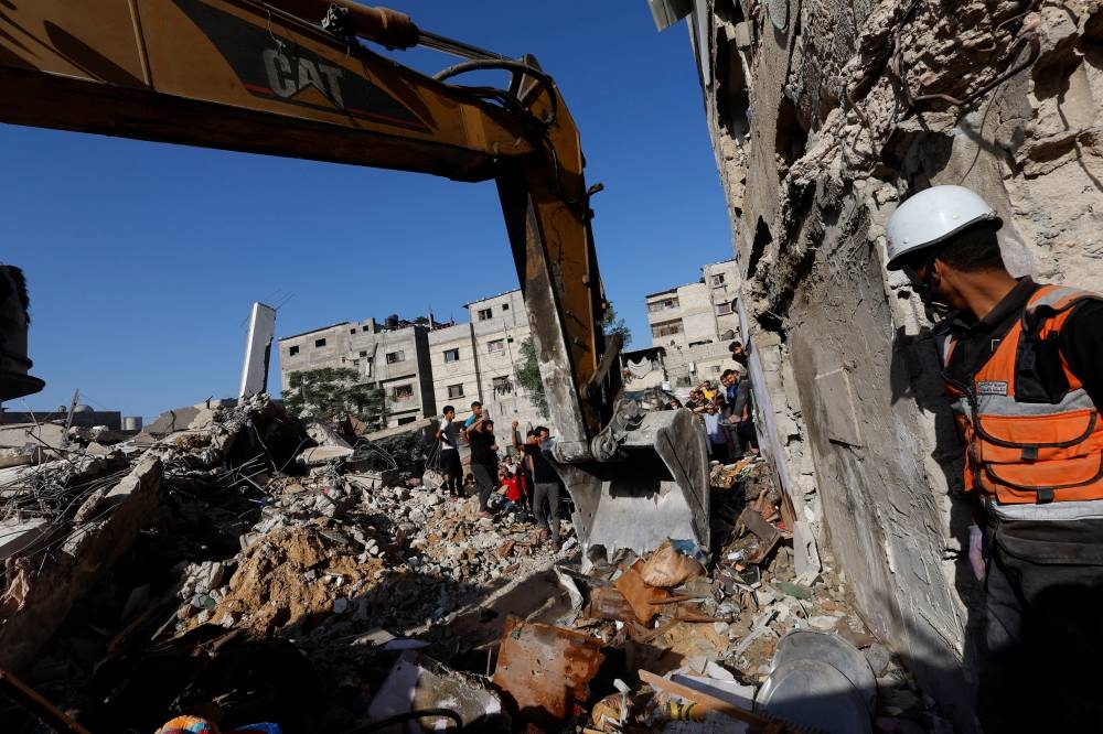 Palestinians gather at the site of Israeli strikes on a residential building, amid the ongoing conflict between Israel and Palestinian Islamist group Hamas, in Khan Younis in the southern Gaza Strip, on Saturday. REUTERS