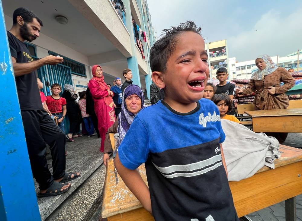 A Palestinian boy reacts at the damages at a UN-run school sheltering displaced people, following an Israeli strike, in Jabalia in the northern Gaza Strip. REUTERS