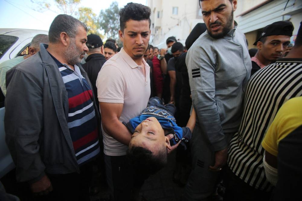 People carry the body of a young boy killed a day earlier in an Israeli strike that hit the entrance of Al-Shifa hospital in Gaza City, reacts during a funeral held for the victims on Saturday. AFP
