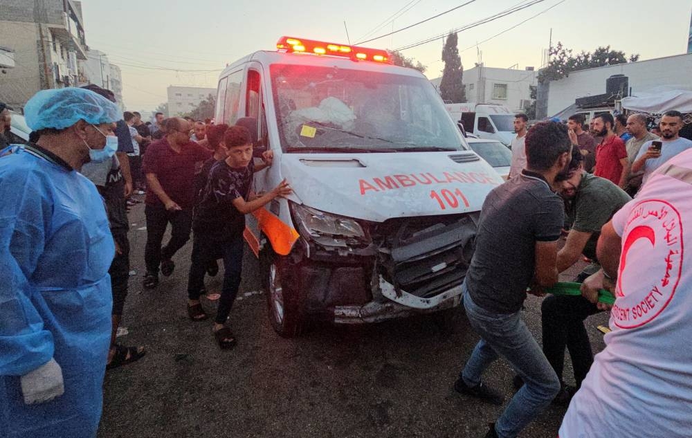 Palestinians pull an ambulance after a convoy of ambulances was hit, at the entrance of Shifa hospital in Gaza City, on Friday. REUTERS