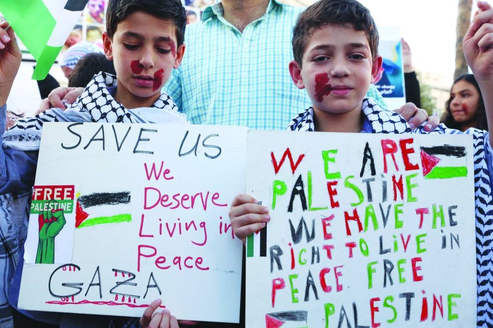 
Palestinian children hold posters during a protest in solidarity with children in the Gaza Strip, in the city of Ramallah, yesterday. 
