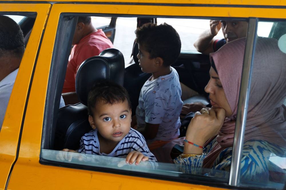A child looks out from a car as Palestinians, including foreign passport holders, wait at Rafah border crossing after evacuations were suspended following an Israeli strike on an ambulance, in Rafah in the southern Gaza Strip, on Sunday. REUTERS